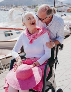 Happy older person in wheelchair smiling at partner. Photo by Rollz International on Unsplash